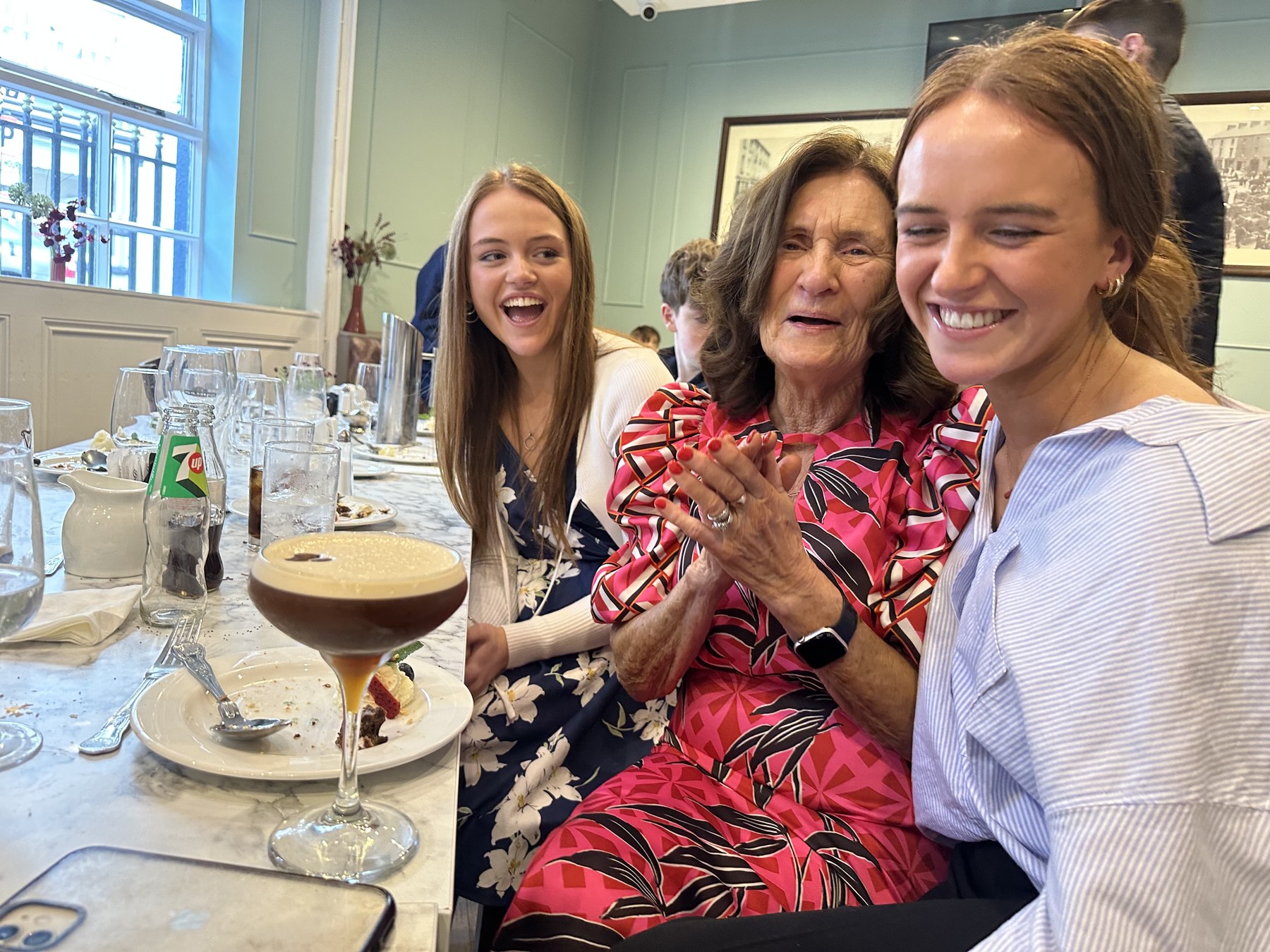 Three people laughing together at a restaurant table.