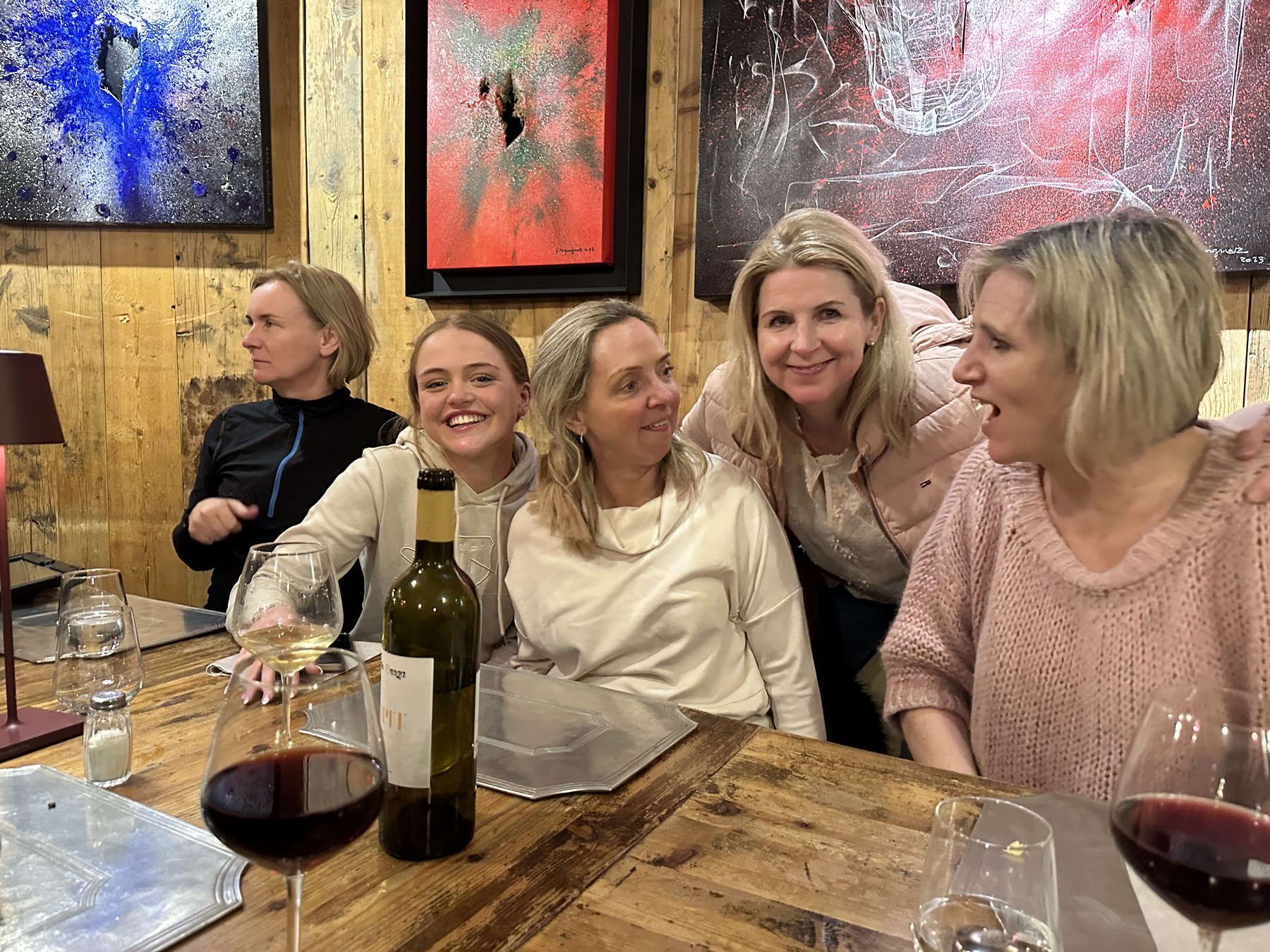 A smiling group sitting together at a wooden restaurant table.