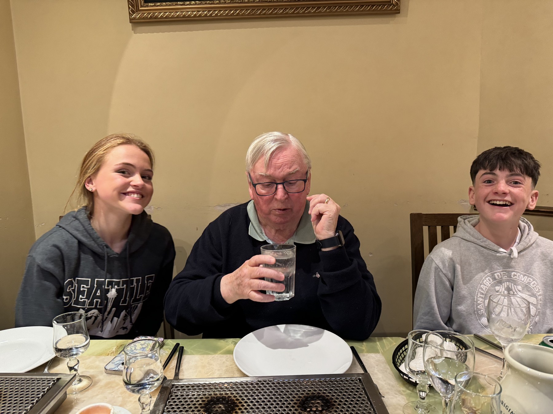 Three people smiling around a dining table.